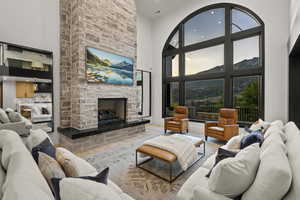 Living area featuring a towering ceiling, a stone fireplace, wood finished floors, and recessed lighting