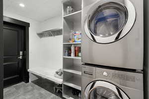 Washroom with stacked washer / drying machine, recessed lighting, and light tile patterned floors