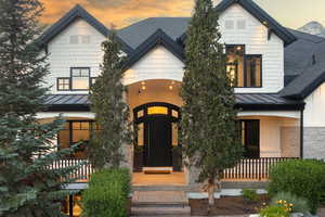 View of front of house featuring a standing seam roof, a shingled roof, covered porch, a metal roof, and stone siding