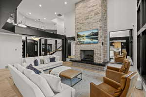 Living area featuring wood finished floors, a high ceiling, a fireplace, stairway, and recessed lighting