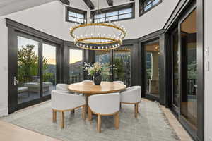Dining space with a chandelier, a high ceiling, wood finished floors, and french doors