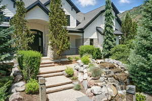 Craftsman-style home with stone siding, covered porch, a standing seam roof, roof with shingles, and a metal roof