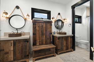 Bathroom featuring two vanities and toilet