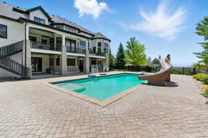 View of pool featuring a water slide, a patio, and stairway