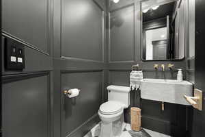 Half bathroom featuring marble look tiles and toilet