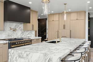 Kitchen with light brown cabinetry, recessed lighting, light stone countertops, extractor fan, and double oven range