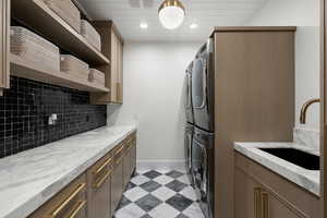 Washroom featuring stacked washing machine and dryer, cabinet space, and recessed lighting
