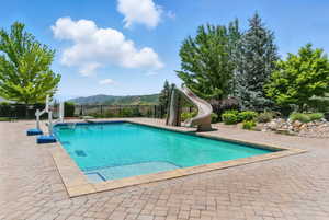 View of swimming pool featuring a water slide, a mountain view, and a patio