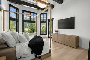 Bedroom with a towering ceiling, light wood-style flooring, and a chandelier
