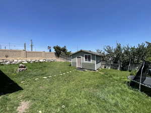 Fenced backyard with a trampoline and an outdoor structure