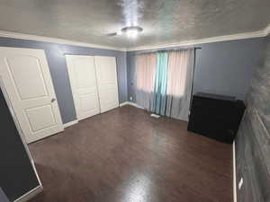 Main bedroom with wood finished floors, a textured ceiling, crown molding, and a closet