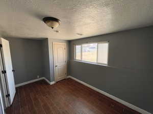 Downstairs bedroom #2 featuring dark wood finished floors and a textured ceiling