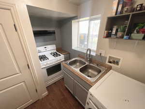 Downstairs Kitchen with white gas range oven, washer. dark wood-style floors, and under cabinet range hood