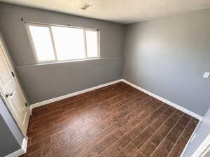 Downstairs bedroom #2 with dark wood finished floors and a textured ceiling