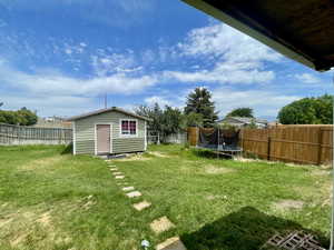 Fenced backyard with a trampoline and an outbuilding