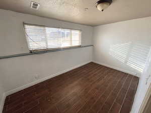 Downstairs bedroom #1 eaturing dark wood-style floors and a textured ceiling