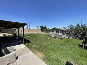 Fenced backyard with a trampoline and an outdoor structure