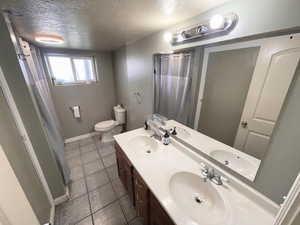 Downstairs Full bath featuring curtained shower, a textured ceiling, and double vanity