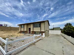 Bi-level home with concrete driveway, a fenced front yard, and brick siding