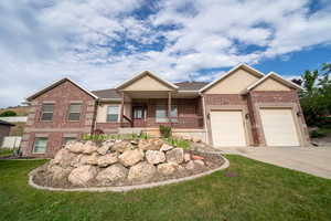 View of front facade featuring brick siding, concrete driveway, a garage, a front lawn, and covered porch