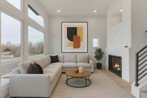 Living room featuring light wood finished floors, recessed lighting, and a glass covered fireplace