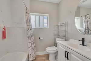 Full bath featuring wood finished floors, vanity, and shower / tub combo with curtain