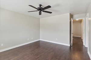 Unfurnished room featuring ceiling fan, dark wood finished floors, and a textured ceiling