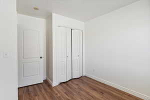 Unfurnished bedroom featuring dark wood-style floors and a closet