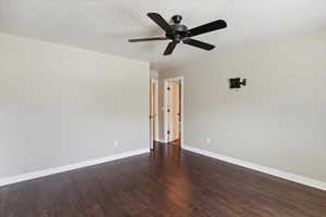 Unfurnished room featuring ceiling fan and dark wood-type flooring