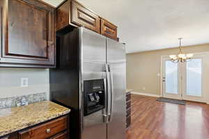 Kitchen with stainless steel fridge with ice dispenser, dark wood-type flooring, a chandelier, and dark brown cabinetry