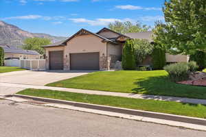 Ranch-style house featuring a garage, stucco siding, concrete driveway, a mountain view, and stone siding
