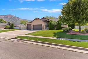 View of front of property with stucco siding, an attached garage, driveway, a mountain view, and stone siding