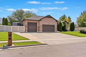 View of front of property featuring an attached garage, driveway, stucco siding, and stone siding