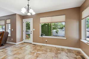 Unfurnished dining area featuring stone finish floors and a chandelier