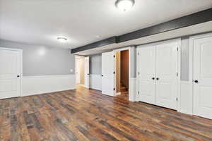 Finished below grade area with wood finished floors, a textured ceiling, and wainscoting