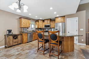 Kitchen with stainless steel appliances, stone tile flooring, a kitchen island, recessed lighting, and a kitchen breakfast bar