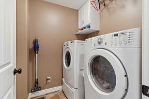 Washroom featuring separate washer and dryer and cabinet space