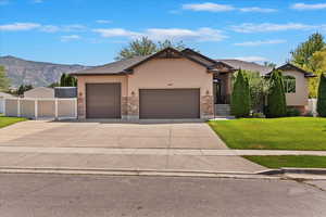 Ranch-style house with stucco siding, a garage, driveway, a mountain view, and stone siding