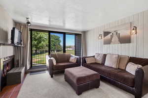 Tiled living area featuring wood walls, a warm lit fireplace, and a textured ceiling