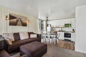 Living area with dark colored carpet, wood walls, and a textured ceiling