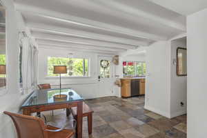Dining space featuring stone tile floors, beamed ceiling, and healthy amount of natural light