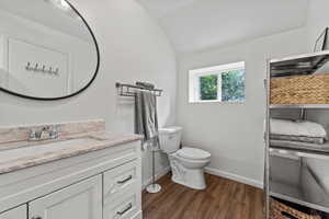 Bathroom with wood finished floors, lofted ceiling, and vanity