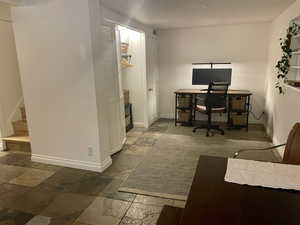 Home office with stone tile flooring and baseboards