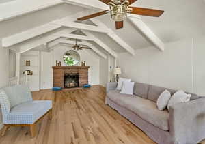 Living room with a ceiling fan, light wood-style floors, and a fireplace