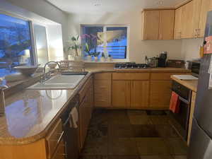 Kitchen with appliances with stainless steel finishes, a peninsula, and light countertops