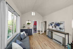 Living area featuring light wood-style floors, wooden ceiling, and high vaulted ceiling