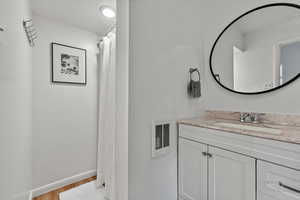 Full bathroom featuring wood finished floors, vanity, and curtained shower