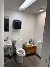 Half bathroom featuring wood finished floors and toilet