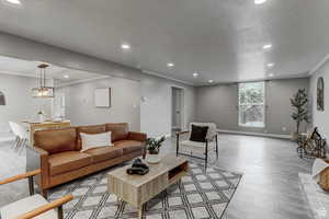 Living area with wood finished floors, recessed lighting, and ornamental molding
