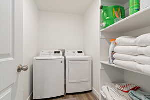Washroom with washing machine and clothes dryer and wood finished floors